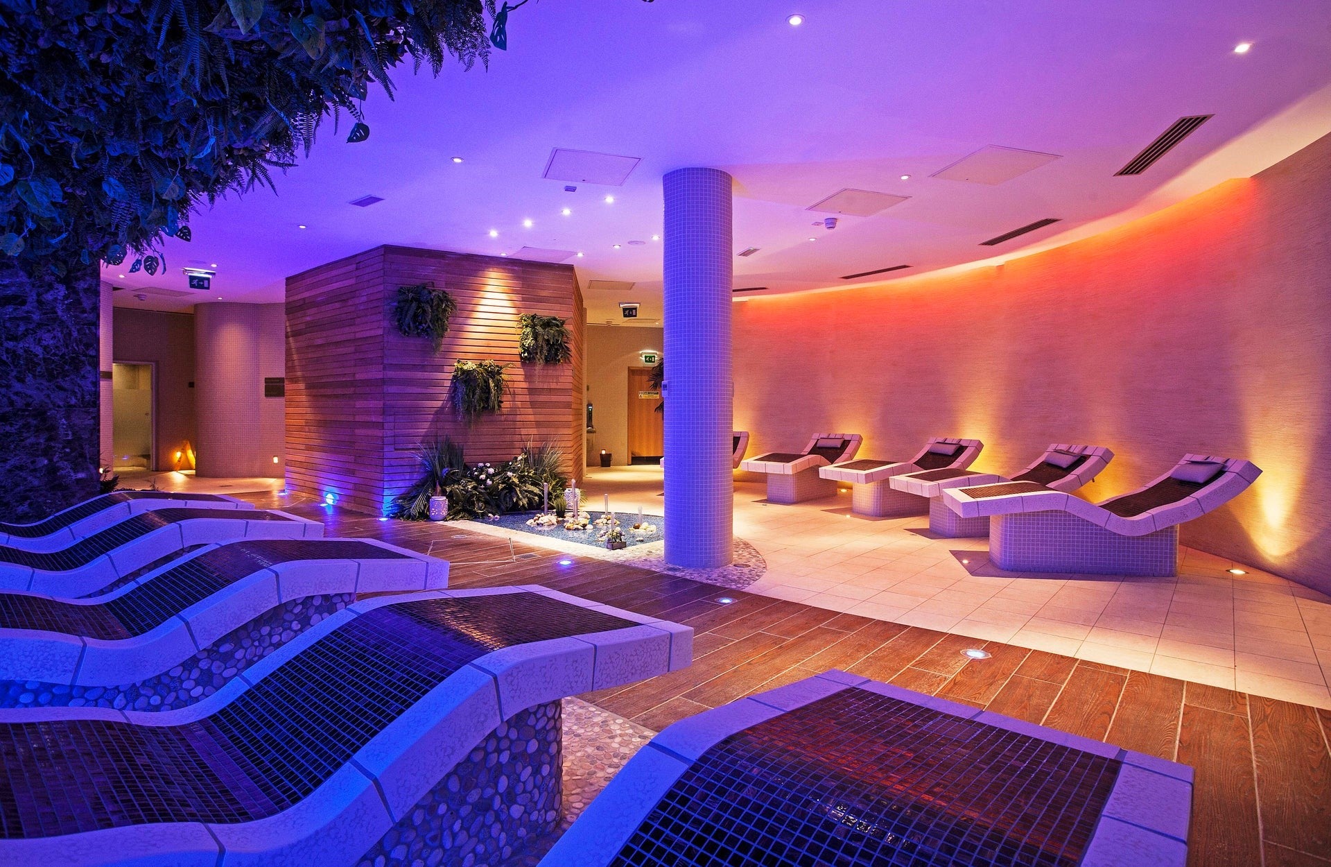 A dimly lit spa with purple lighting and reclined seating