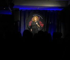 A comedian holding a microphone on a stage