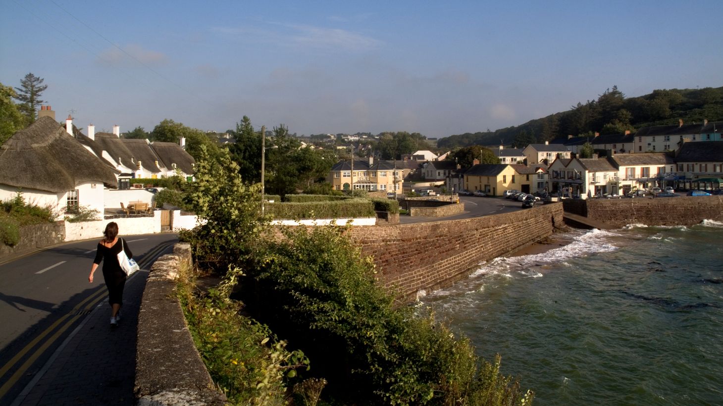 Woman walking on a country road beside the sea in Dunmore East, Waterford