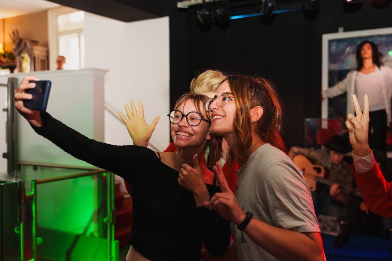 Two ladies take a selfie with a wax effigy of Michael Jackson blurred in the background