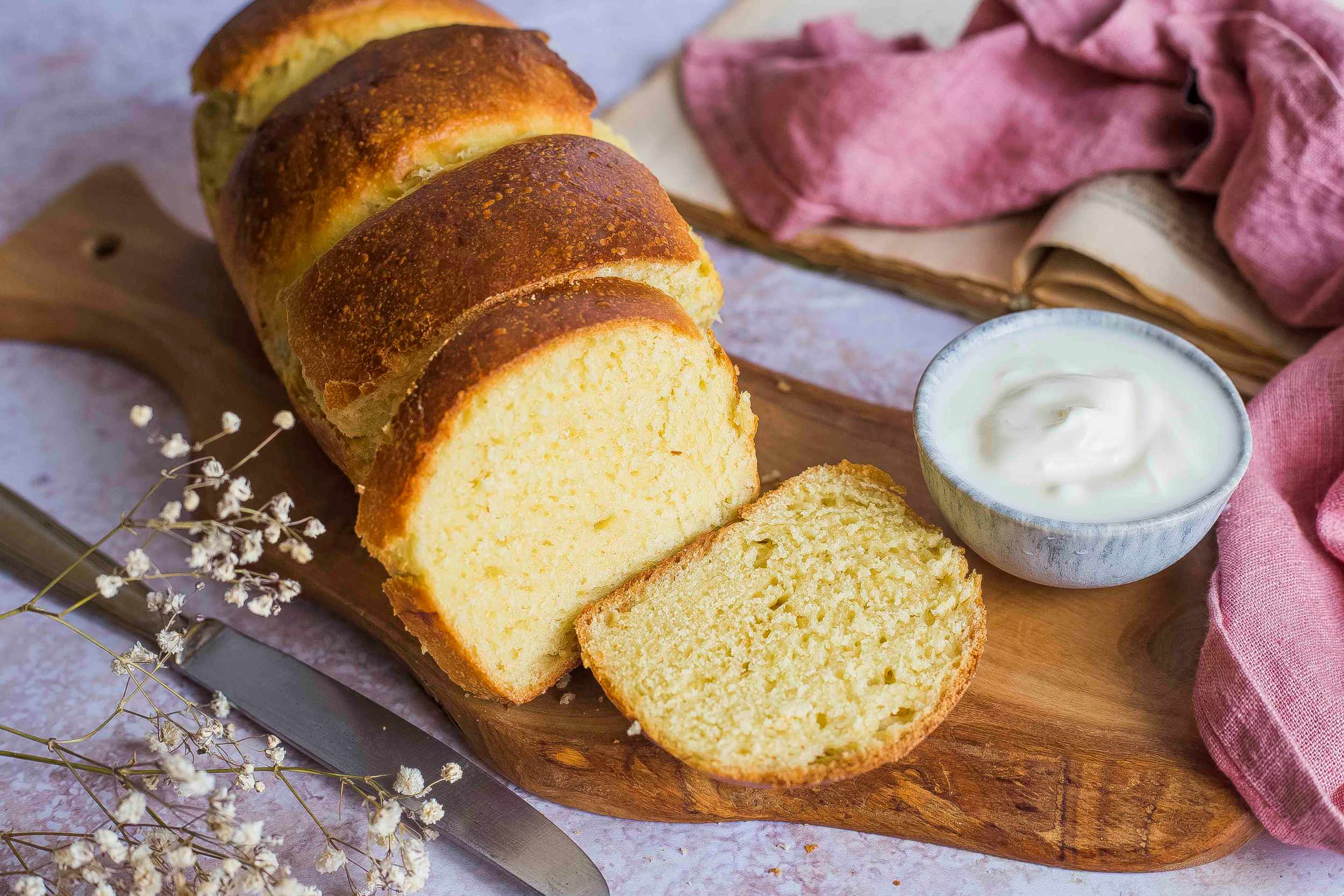 Pan brioche con yogurt Latte Fieno, disposto su tagliere di legno con ciotolina di yogurt accanto
