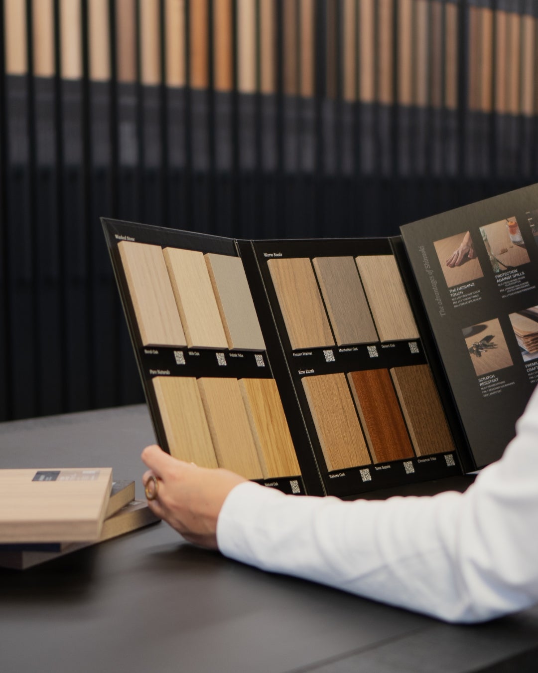 A person looking at a wood veneer panels - sample book - Shinnoki