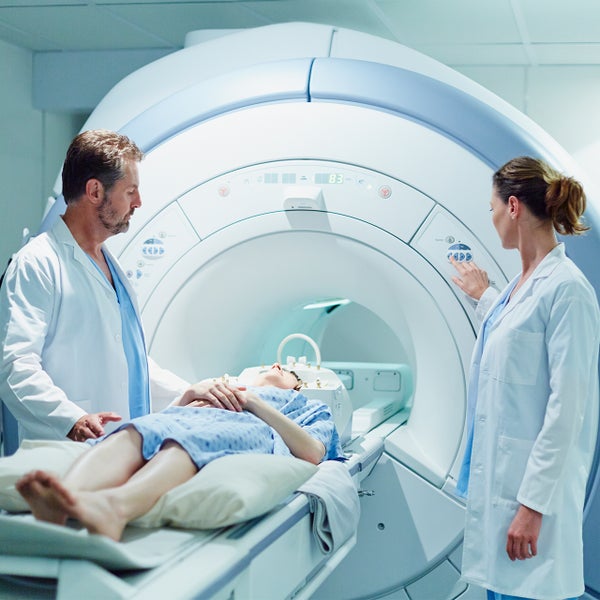 Patiënt in MRI met artsen er naast