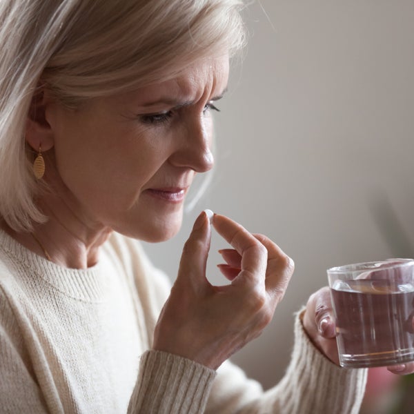 Vrouw neemt een pil in met een glaasje water.