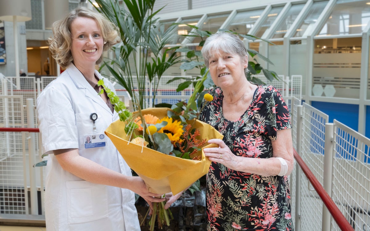 Een zorgverlener overhandigt een patiënt een boeket bloemen omdat de patiënt de 600e longtransplantatie heeft ondergaan.