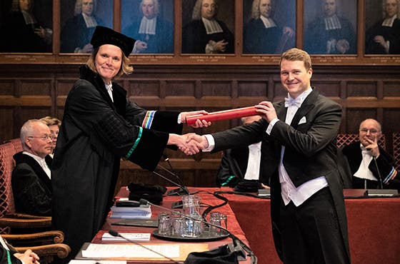 Graduate receiving his diploma from a professor in traditional academic attire during a ceremony