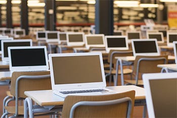 Collegezaal opstelling met laptops voor digitaal toetsen