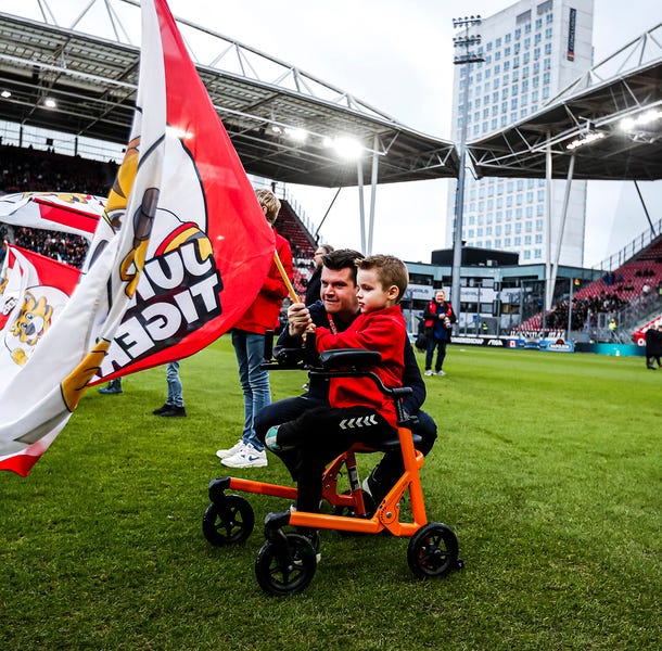 Een kleine jongen en zijn ouder/verzorger houden een FC Utrecht-vlag vast op het voetbalveld van Galgenwaard tijdens de WKZ-week van FC Utrecht.