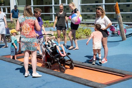 Kinderen spelen in de nieuwe binnentuin van het WKZ terwijl de ouders toekijken.