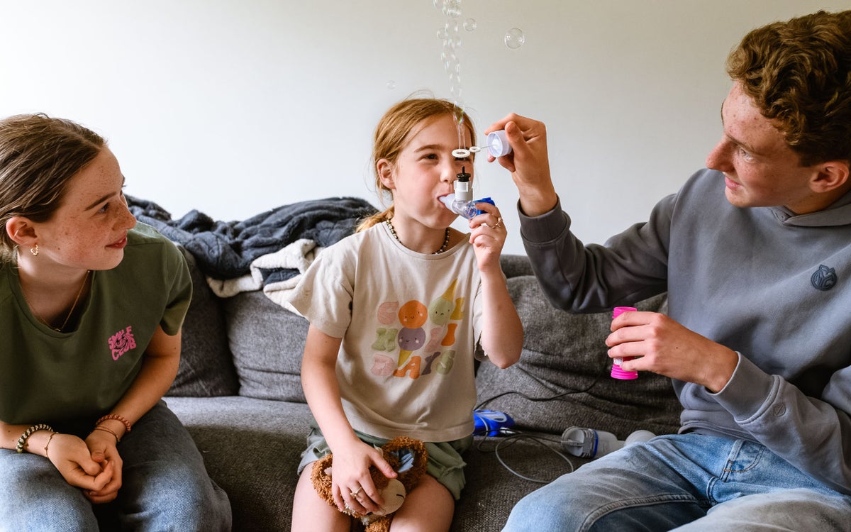 Veerle heeft cystic fibrosis (CF) en neemt medicijnen met een pufje in. Haar broer houdt een bellenblaas boven de uitlaat van het pufje, zodat er bubbels verschijnen.