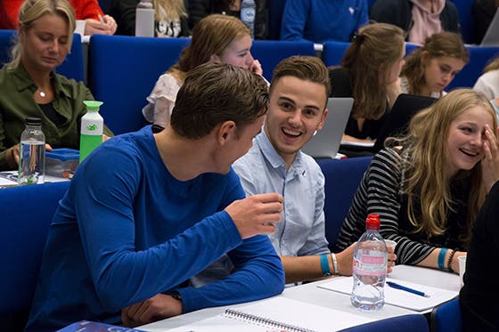 Studenten lachen en praten samen tijdens een interactieve les in een collegezaal