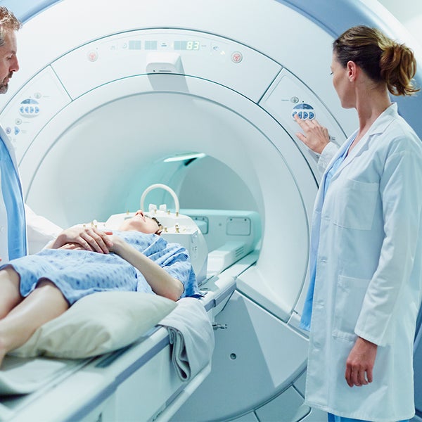 Patiënt in MRI met artsen er naast