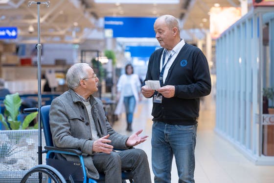 Een vrijwilliger in gesprek met een man in een rolstoel