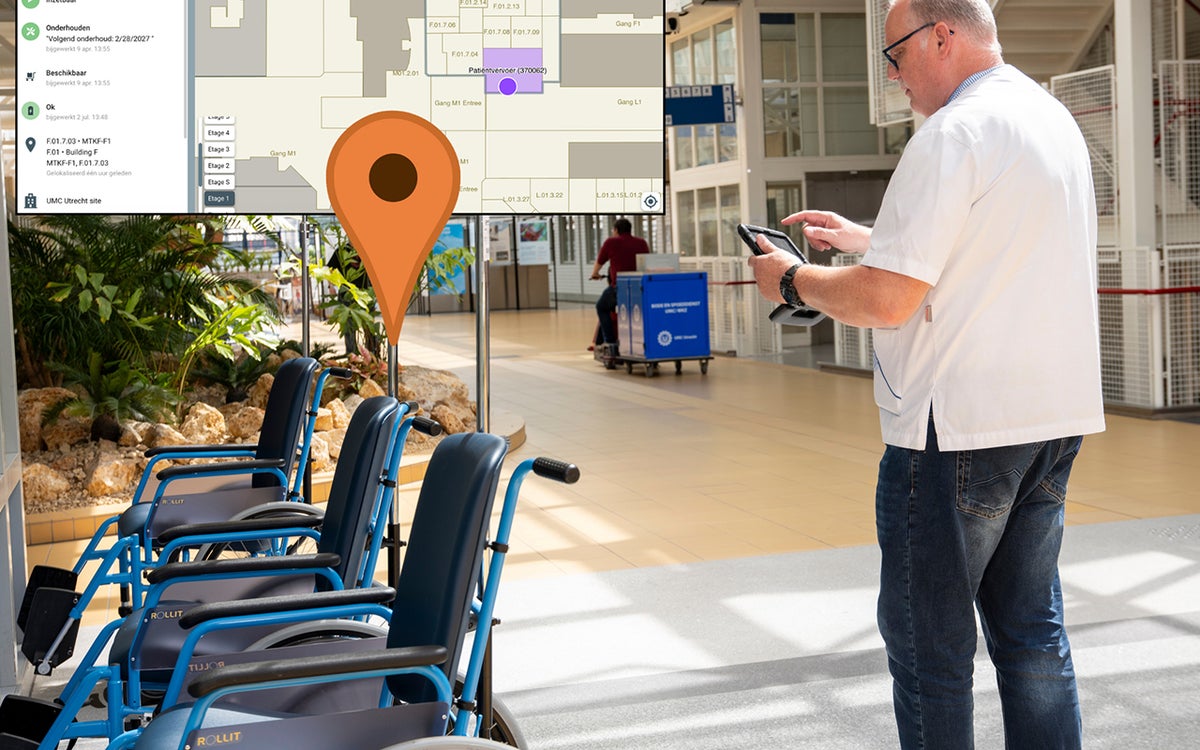 UMC Utrecht medewerker staat naast rolstoelen en kijkt op tablet