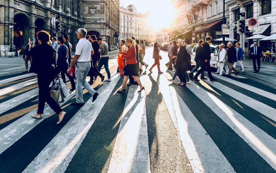 Mensen lopen op een zebrapad in een stad.