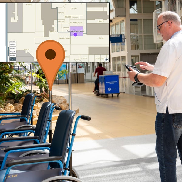 UMC Utrecht medewerker staat naast rolstoelen en kijkt op tablet