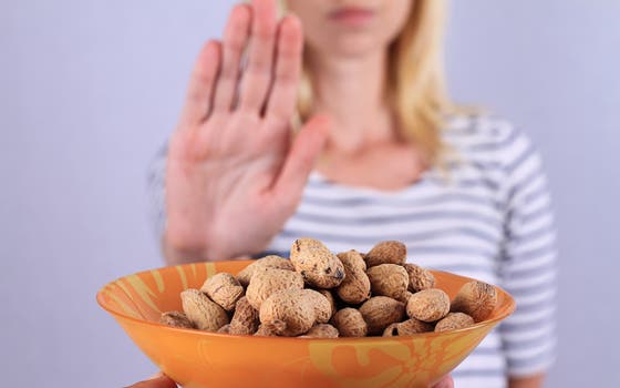 Woman gestures No to offered bowl with peanuts