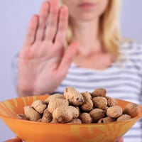 Woman gestures No to offered bowl with peanuts