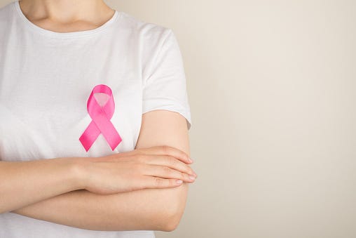 Een vrouw met een Pink Ribbon op haar borst.