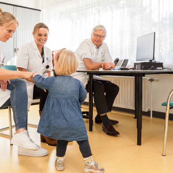 Peuter geeft een boks aan de regiebehandelaar. Twee andere zorgverleners kijken toe.