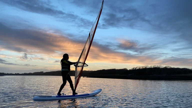 A person on a surfboard with a sail