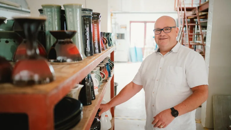 A man standing next to a shelf with vases