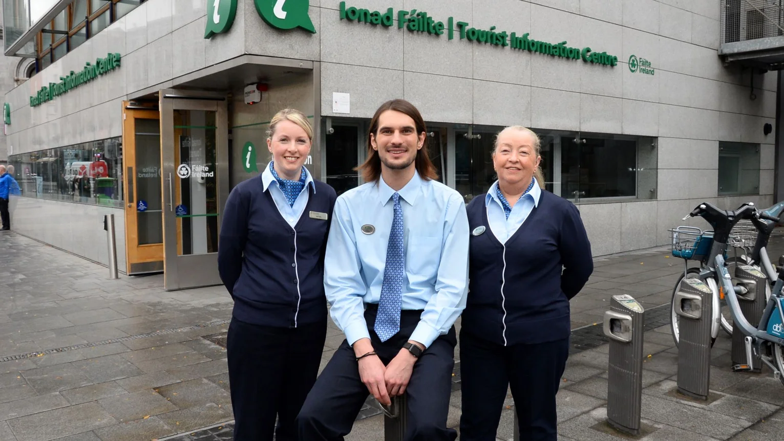Three staff members standing outside a Fáilte Ireland tourist information centre