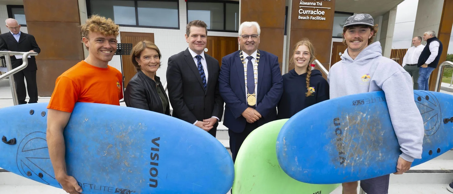 Stakeholders and people with surfboards pose for a photo in front of the new water sports centre.