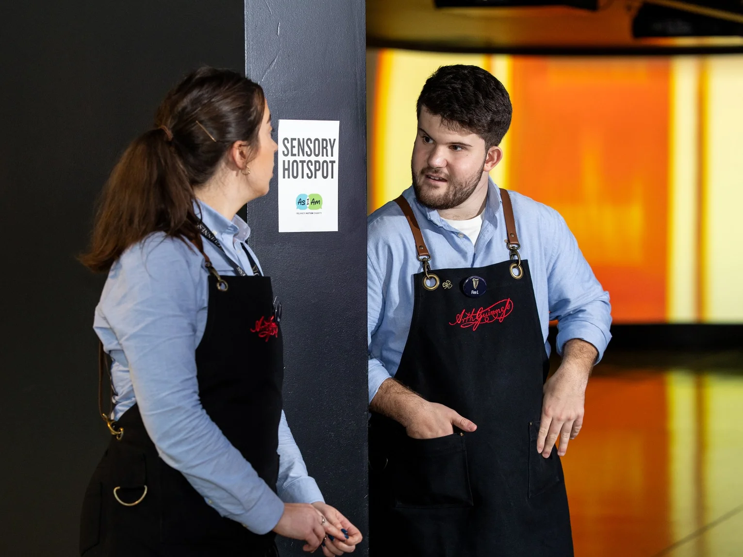 Two staff members in Guinness Storehouse aprons in conversation beside a sensory hotspot display