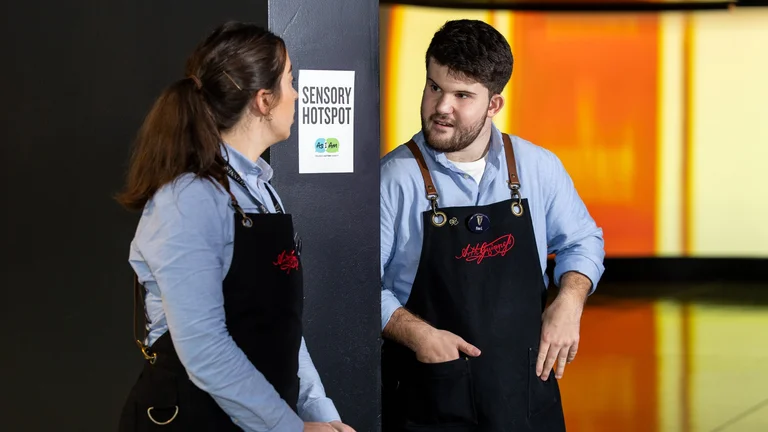Two staff members in Guinness Storehouse aprons in conversation beside a sensory hotspot display