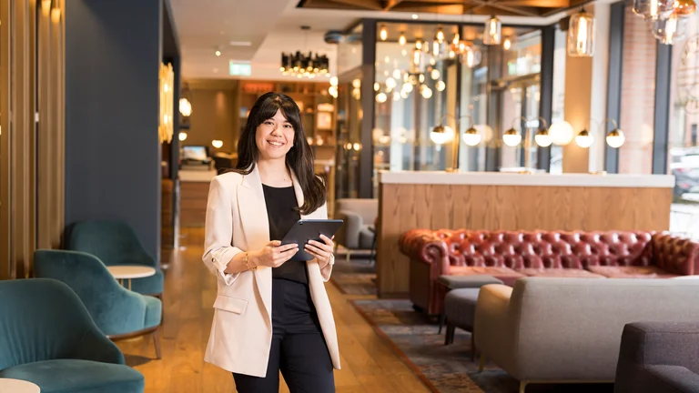 A woman standing in a room with a tablet