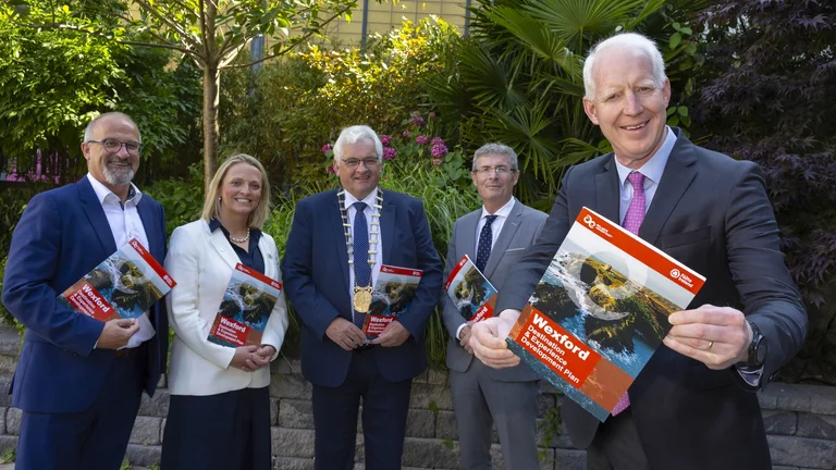 Stakeholders pose for photo holding copies of DEDP document