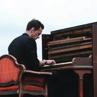 Niall Breslin playing an upright piano outdoors