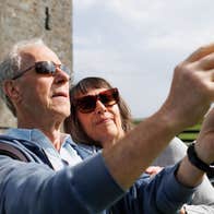 Two people wearing sunglasses taking a picture in front of a castle
