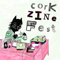 A cat at a desk, making a zine.