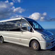 Mercedes tour bus with sea and blue sky in the background