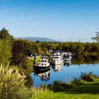 Cruisers moored at Leitrim Village in County Leitrim on a sunny day near some trees