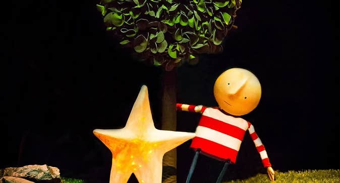 How To Catch A Star, a puppet with bald head and stripy top, swinging from a tree, beside a large gold star.