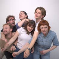 A group of 6 people standing, intertwined with each other.