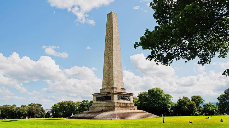 Wellington monument in Phoenix Park on a sunny day with blue skies and bright green grass surrounding it.