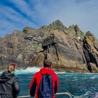 Three passengers on a tour boat taking photos of Small Skellig island