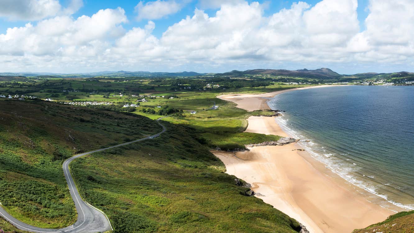 A view of a beach with a road twisting along side it