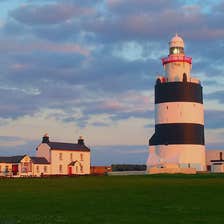 Blue skies over towering  Hook Lighthouse with cottages in the background