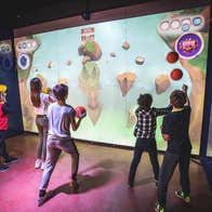Children in a gaming room throwing balls at an interactive wall