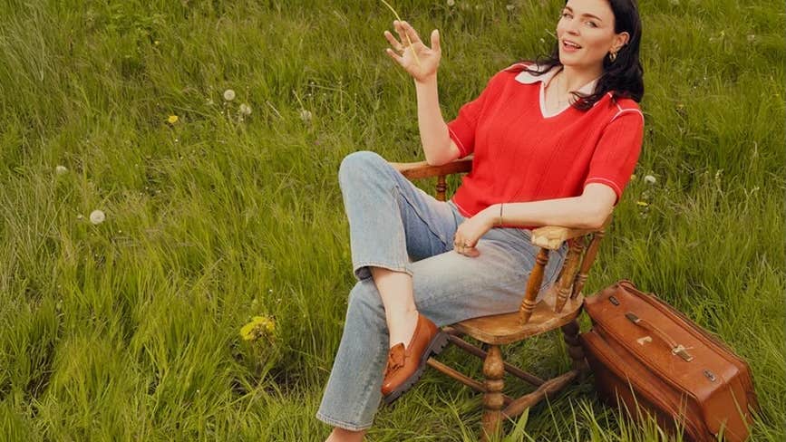 A woman seated in a wooden chair on grass
