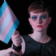 Roadkill Dublin Municipal Theatre at Smock Alley, a sad looking person wearing thick make-up, holding a small, stripy flag.