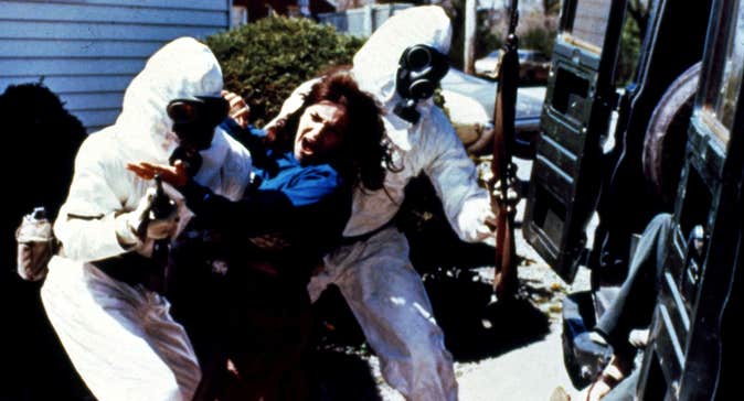 Armed men in hazmat suits are forcing a woman into a vehicle.