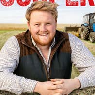 An Evening with Kaleb Cooper, a smiling man resting hands on bale with field behind him