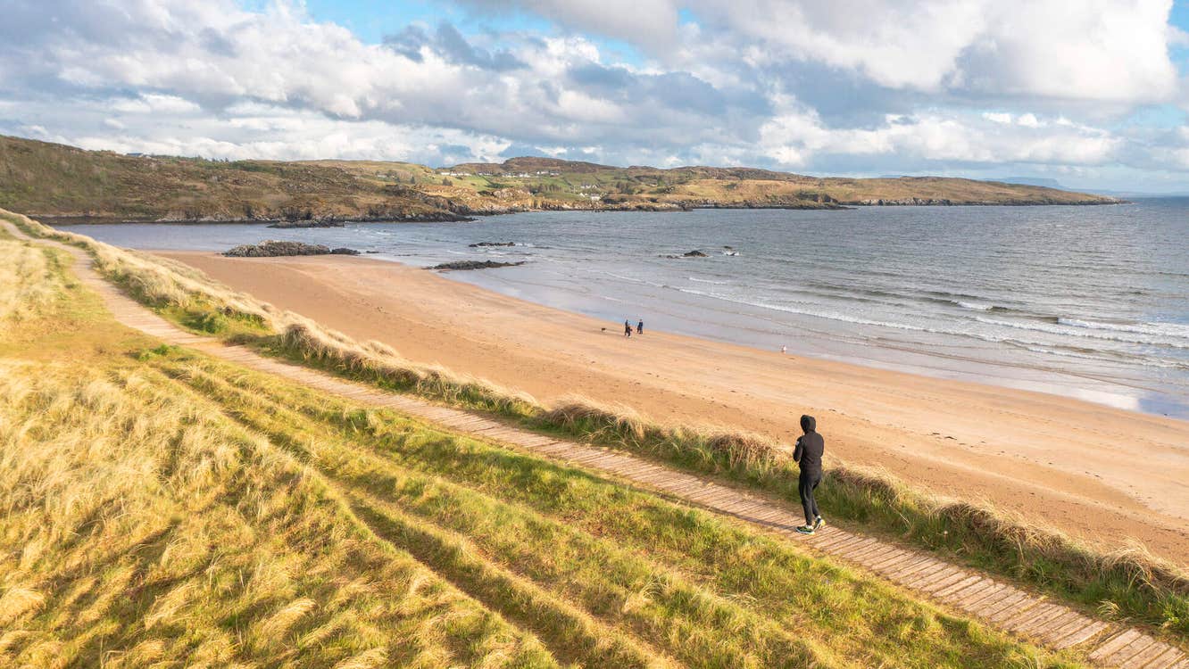Person walking the boardwalk pathway onto Fintra Beach