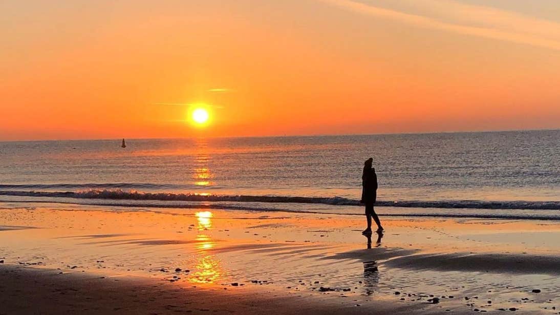A person walking down Morriscastle Beach, County Wexford at sunset.